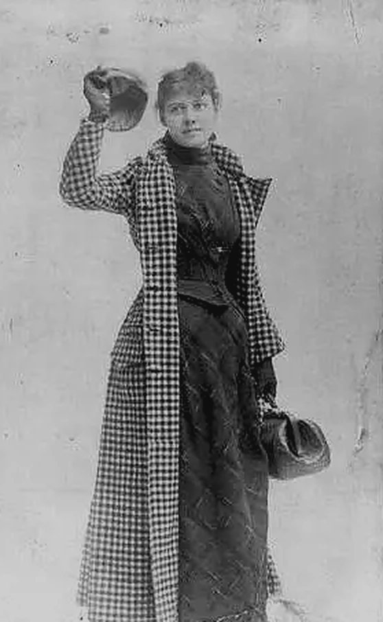 Nellie Bly in 1890, wearing her checked travelling coat and holding the bag she carried around the world